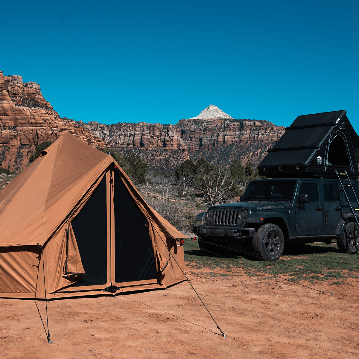 Brown tent and green Jeep with roof rack in desert landscape