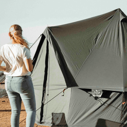Person standing next to a large green tent in an outdoor setting